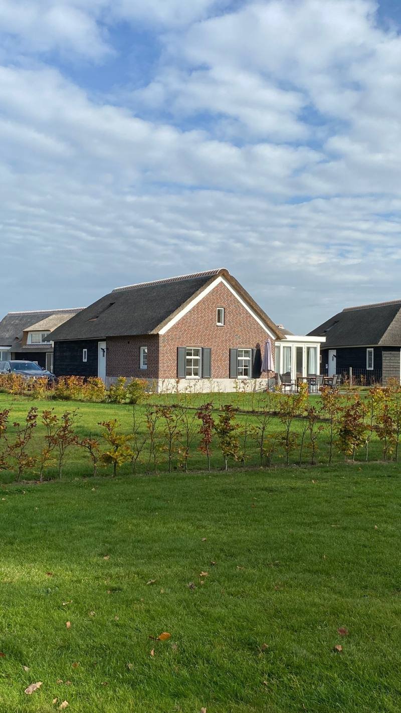A single-storey farm villa with a lawn under a wide sky